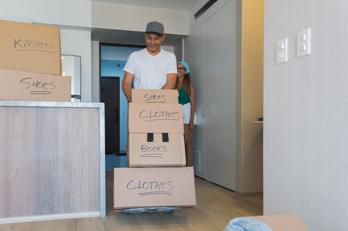 Man and woman moving boxes into new apartment with labeled boxes