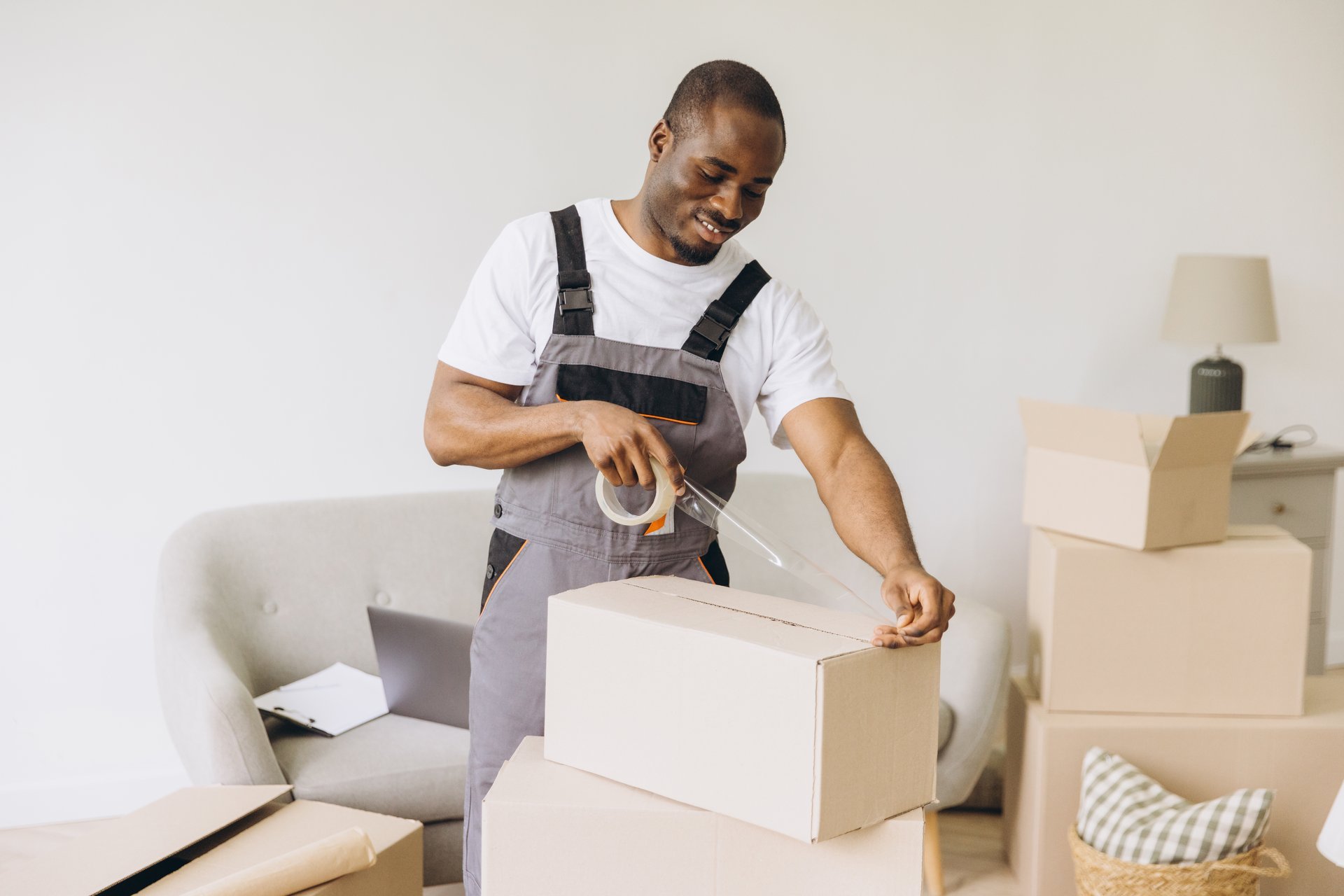 Professional mover taping cardboard box for house relocation